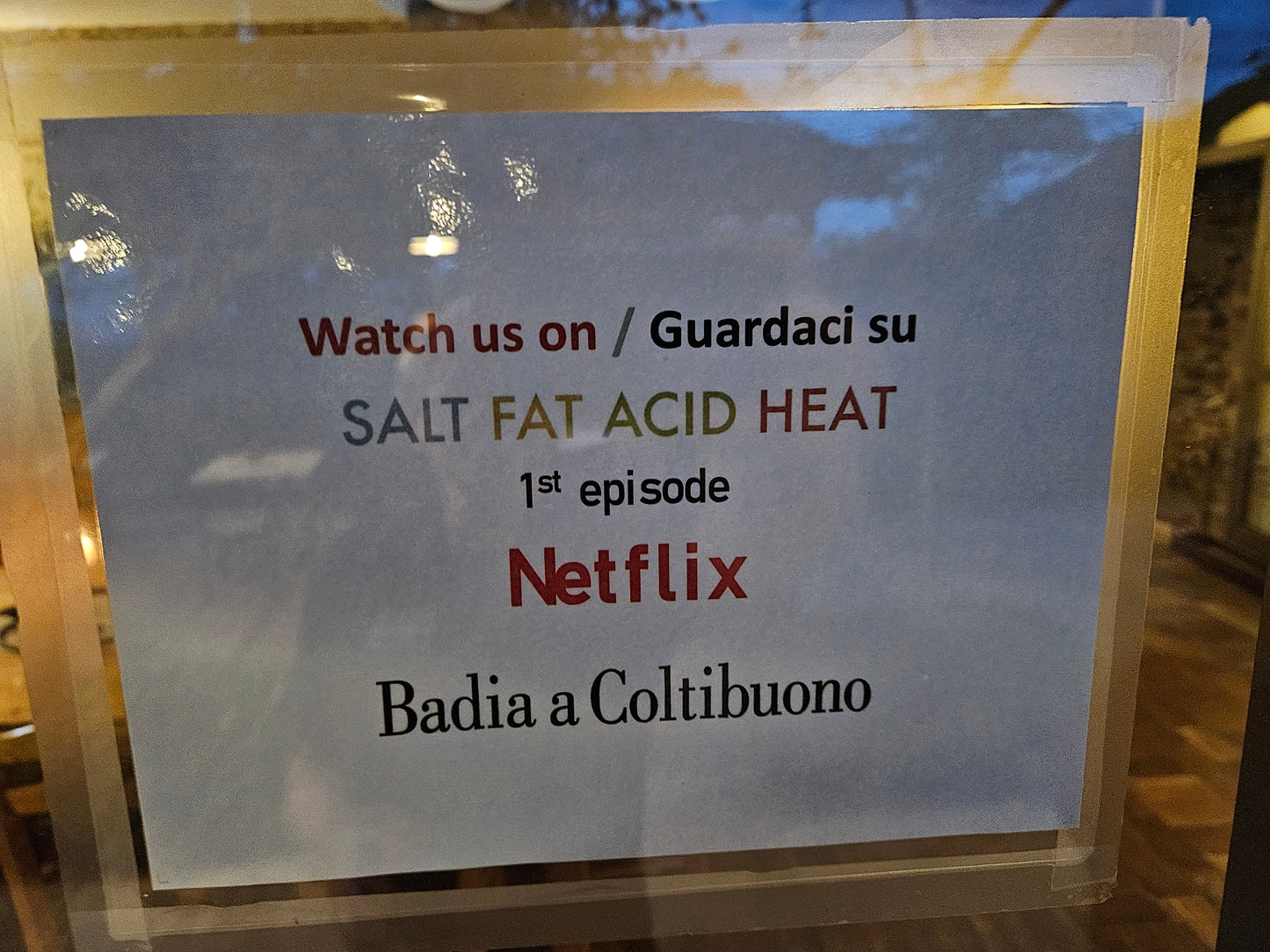 Sign with “Watch us on Netflix” and “Badia a Coltibuono” text inside a clear holder