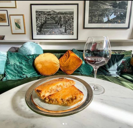 Grilled cheese sandwich on a plate beside a glass of red wine on a table