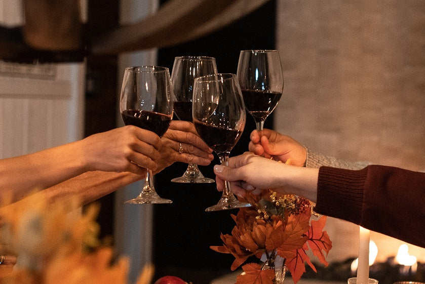 Hands raising glasses of red wine in a Friendsgiving toast