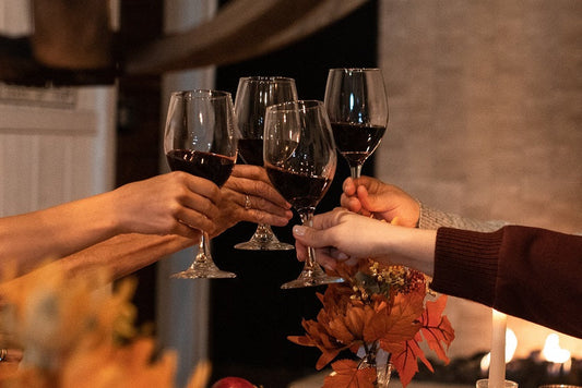 Hands raising glasses of red wine in a Friendsgiving toast