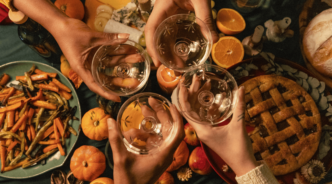 Guests raising wine glasses over a festive table filled with seasonal foods, creating a warm holiday gathering.
