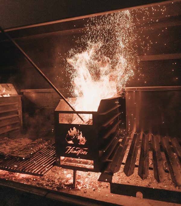 Flames and sparks from a barbecue grill in a dark cooking area