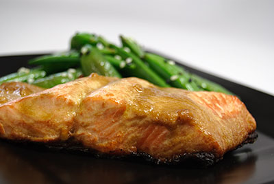 Seared salmon fillet with green beans on a black plate