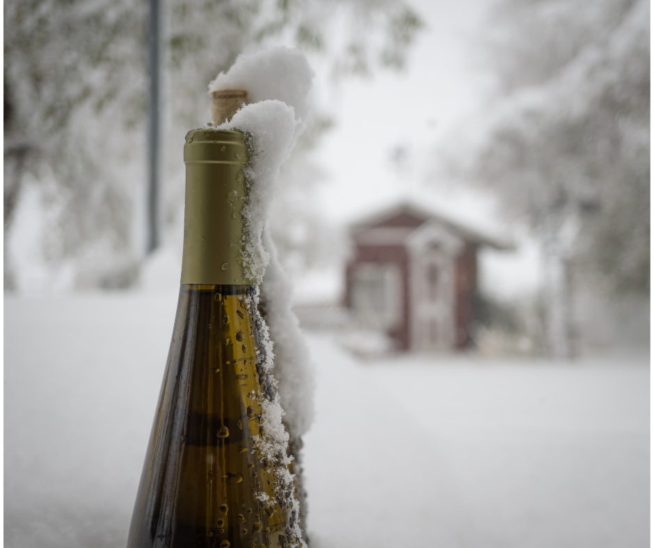 Wine bottle capped with snow outdoors in winter