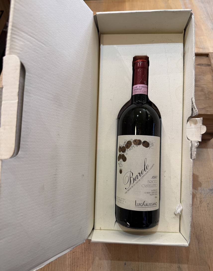 Red wine bottle in its original white box on a wooden surface - 1993 Barolo, Luigi Calissano