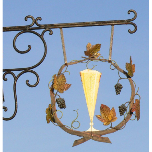 Decorative wrought iron sign with a Champagne glass and leaves against a clear blue sky