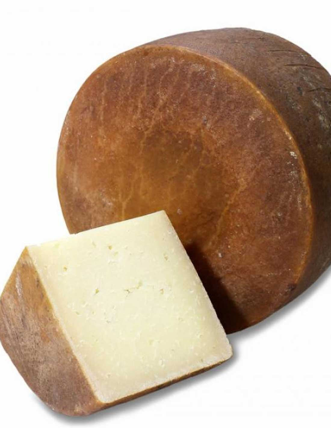 Humo cheese wheel with a cut wedge showing its pale interior and brown rind