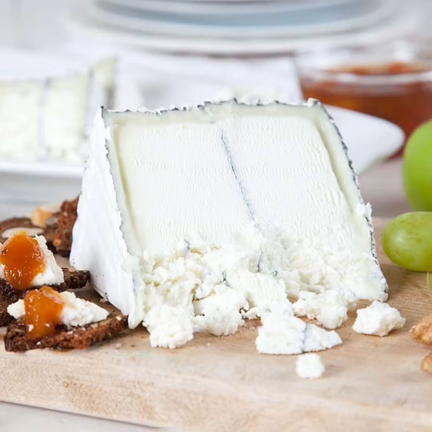 A wedge of fresh Humboldt Fog on a cheese board, showing its crumbly texture when young.
