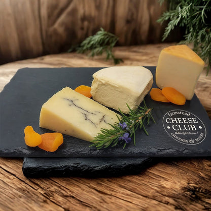 Assorted cheeses on a slate board with apricots and rosemary, branded 'Farmstead Cheese Club'.