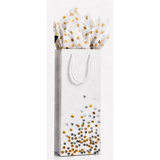 A white gift bag with white rope handles and a pattern of gold, silver, and white confetti at the bottom, filled with white tissue paper featuring gold polka dots, on a white background.