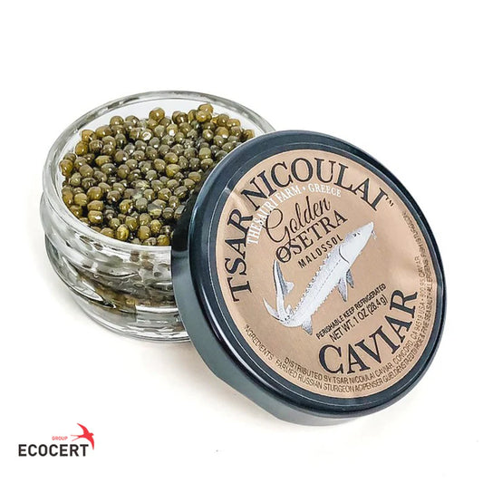 A small clear glass jar filled with greenish-brown caviar sits beside a round black-lidded label that reads Tsar Nicoulai Golden Osetra Madosel Caviar, on a white background.