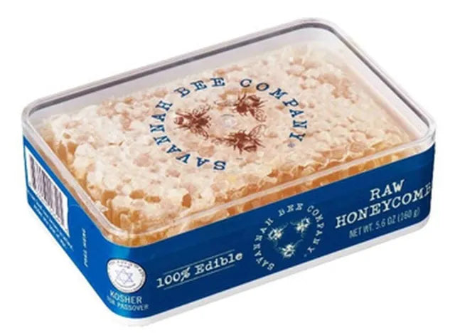 Raw honeycomb inside a plastic container with a clear lid, against a white background