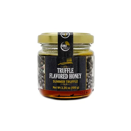 small jar of dark honey imbued with truffles on a white background.