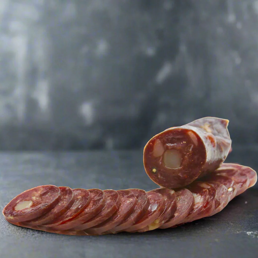 Sliced salami on a dark surface with a blurred background