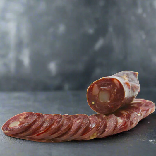 Sliced salami on a dark surface with a blurred background