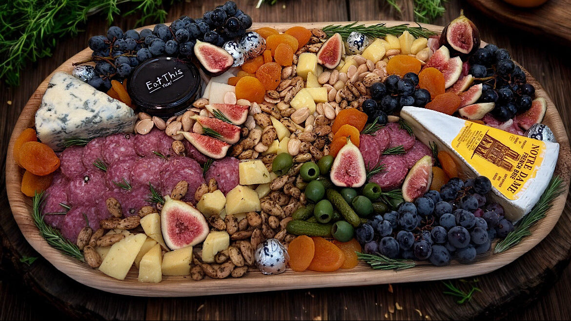Assorted charcuterie board with meats, cheeses, fruits, and nuts on a wooden board.