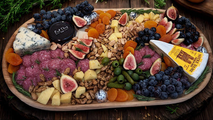 Assorted charcuterie board with meats, cheeses, fruits, and nuts on a wooden board.