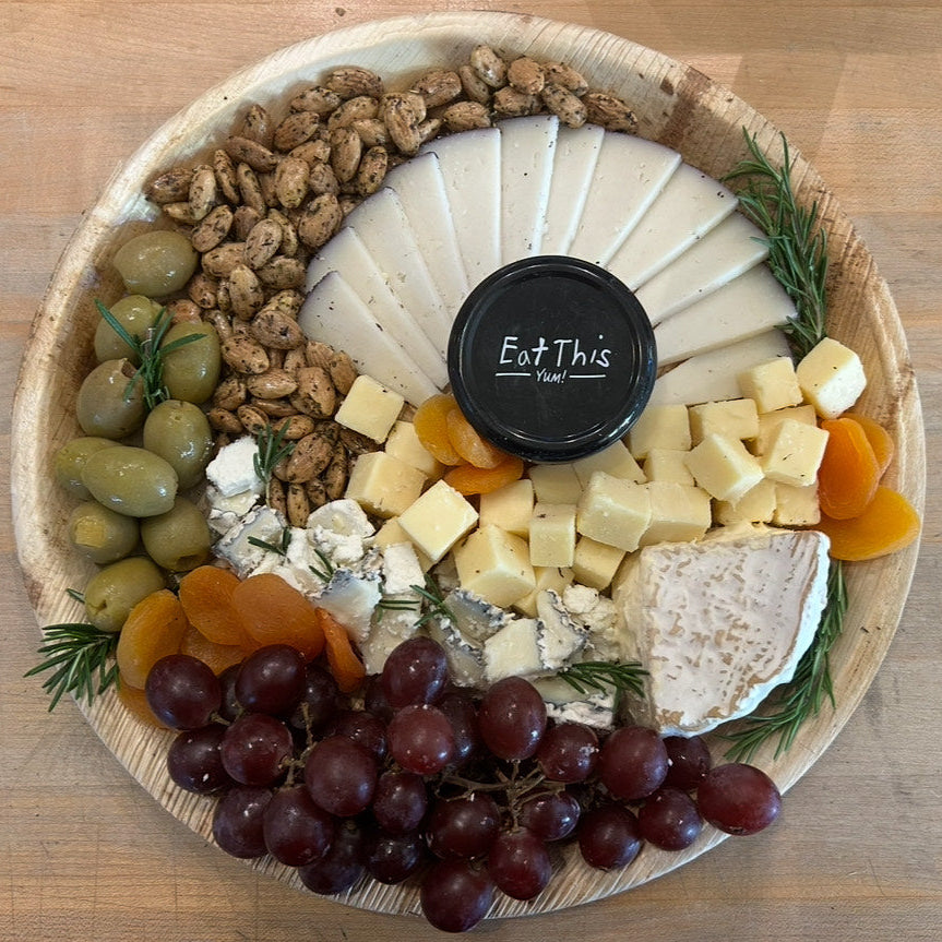 Vegetarian assorted cheese and fruit platter on a wooden board with 'Eat This' jam.