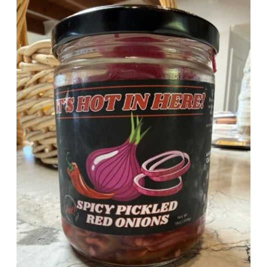 Jar of spicy pickled red onions with a black lid on a woven surface.