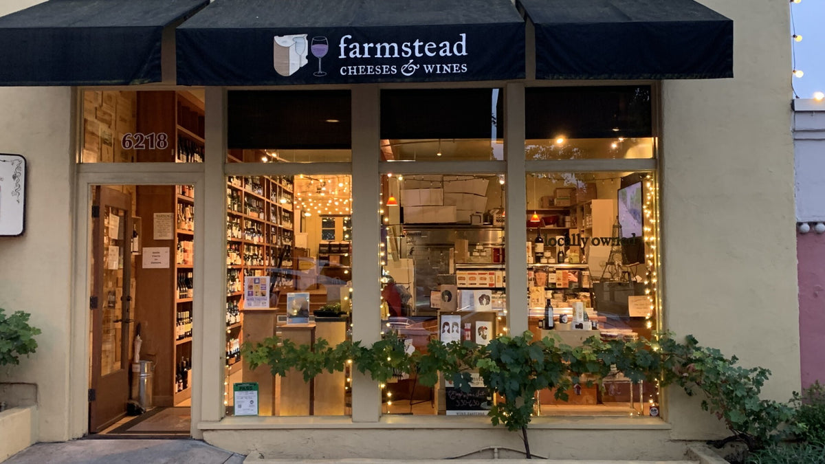 Farmstead Cheeses & Wines storefront lit up at dusk