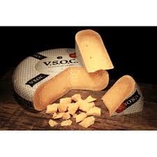 Block of cheese with a piece cut off, branded 'VSOG', on a dark surface.