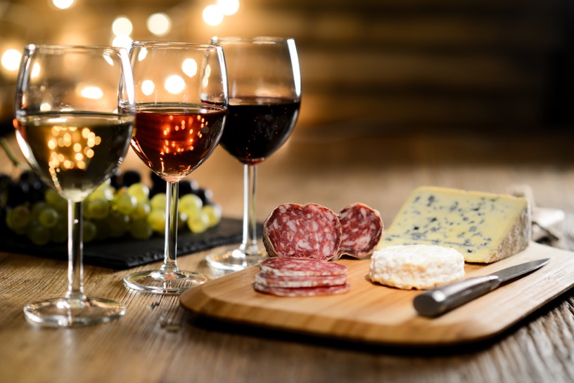 three glass of red wine, rose wine and white wine with blue cheese and delicatessen in restaurant wooden table with romantic dim light and cozy atmosphere